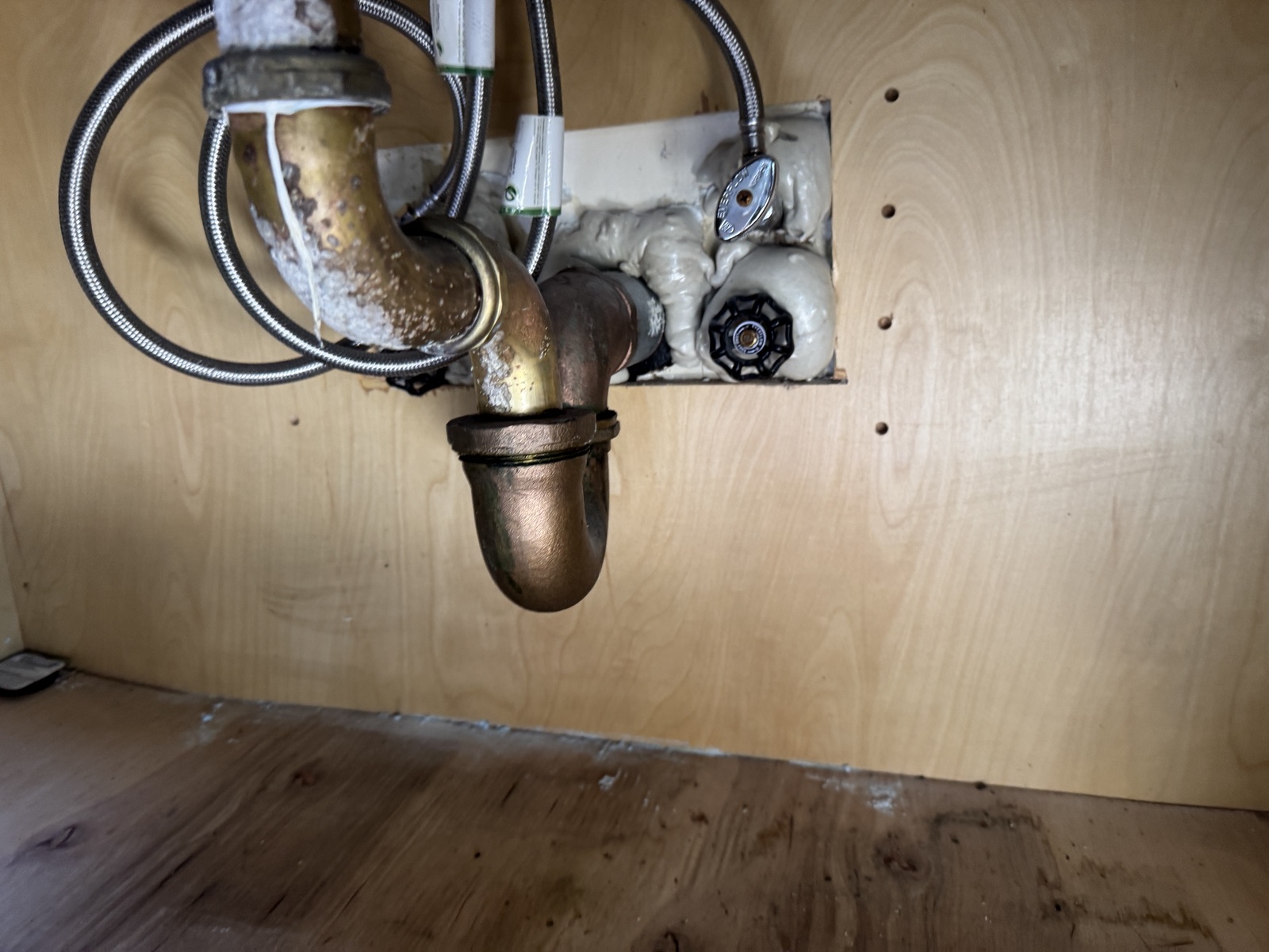 Foam visible around plumbing penetrations in a wooden cabinet